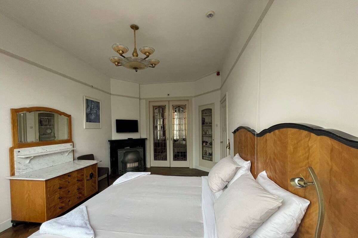 Ein Schlafzimmer mit einem großen Bett, einem Holzkopfteil, einem Schminktisch, einem Fernseher und einem Kamin.