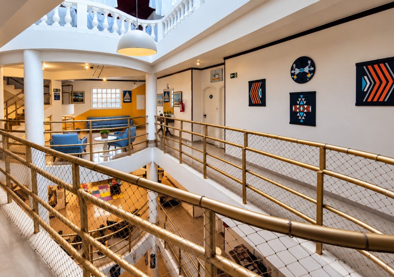 A multi-level interior with a central staircase, a seating area with blue sofas, and artwork on the walls.