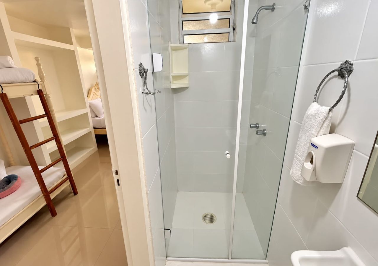 A hotel bathroom with a glass-enclosed shower, a wooden ladder, and a towel dispenser.