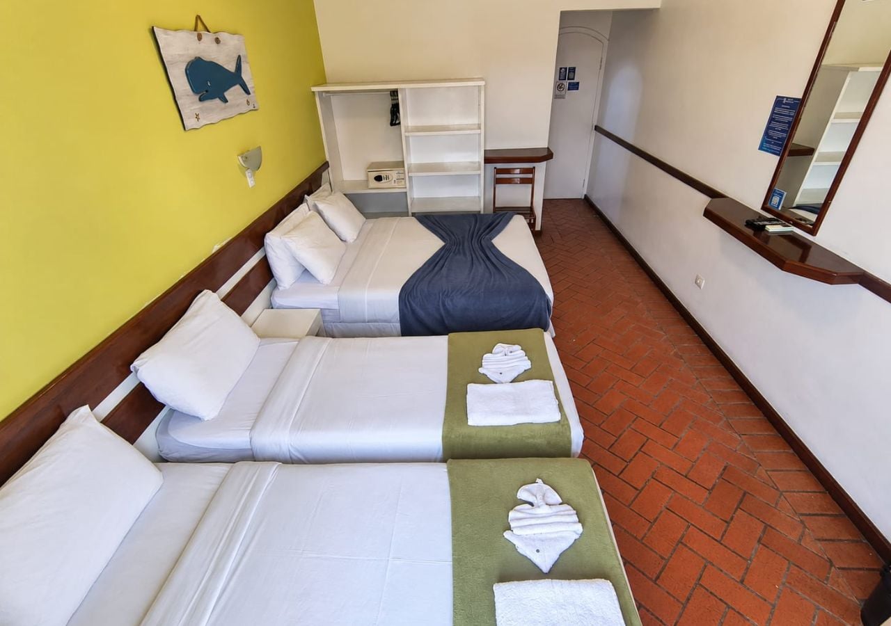 A hotel room with two beds, a desk, a wardrobe, and a mirror.