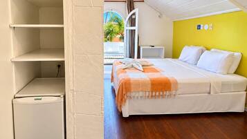 A bedroom with a bed, a bedside table, a small white cabinet, and a view of the outside.