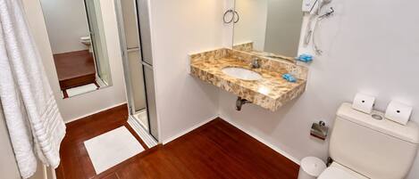 Baño con lavamanos de mármol, inodoro y ducha.