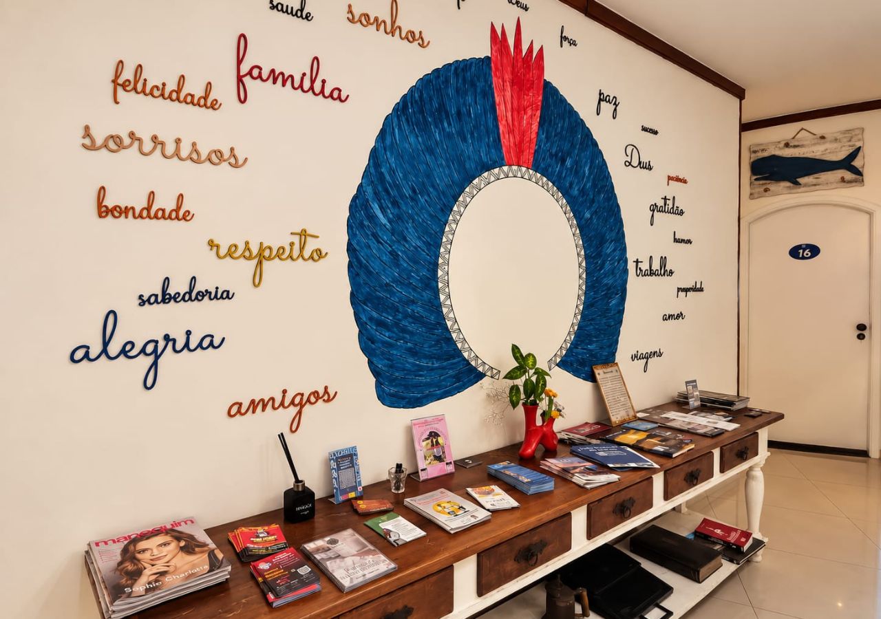 Una habitación con una pared decorada con palabras en varios idiomas, un escritorio de madera con libros y revistas, y una puerta con un número.