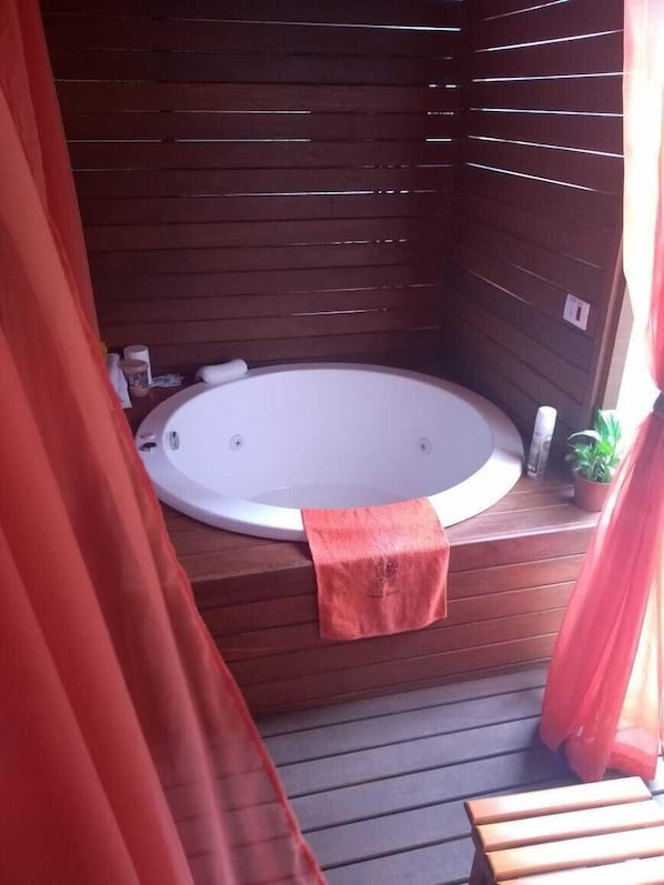 Un bain à remous dans un chalet en bois, avec une serviette posée sur le bord.