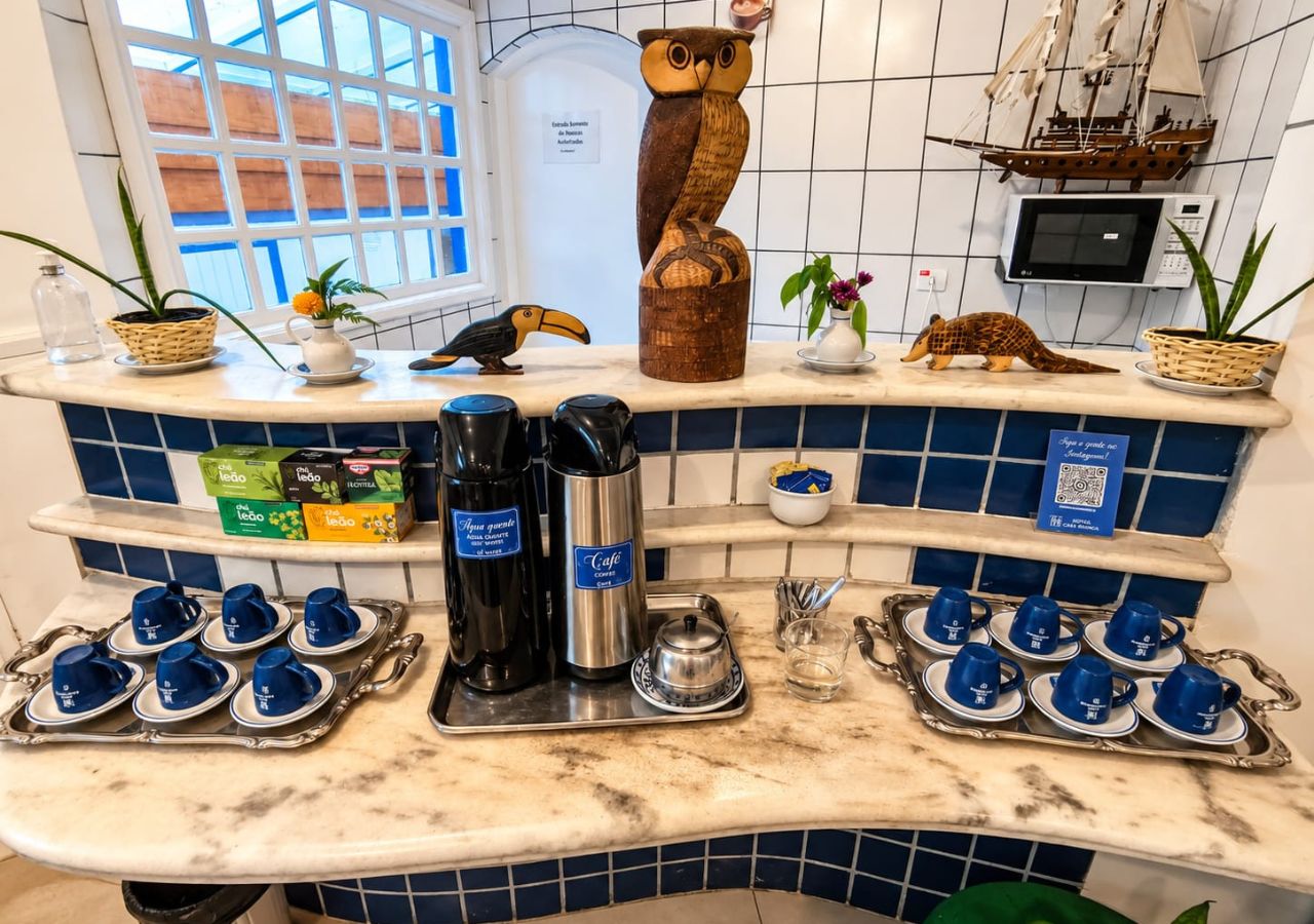 Un comptoir de cuisine avec des machines à café, des boîtes à thé et des objets décoratifs, comme un bateau et une chouette.