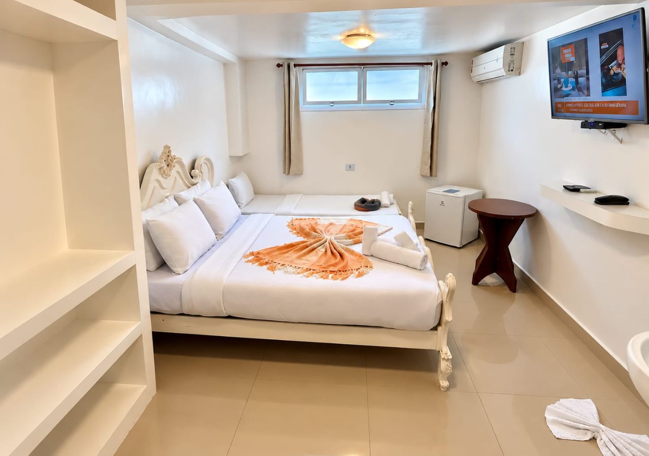 A hotel room with a bed, a TV, a small table, and a window.