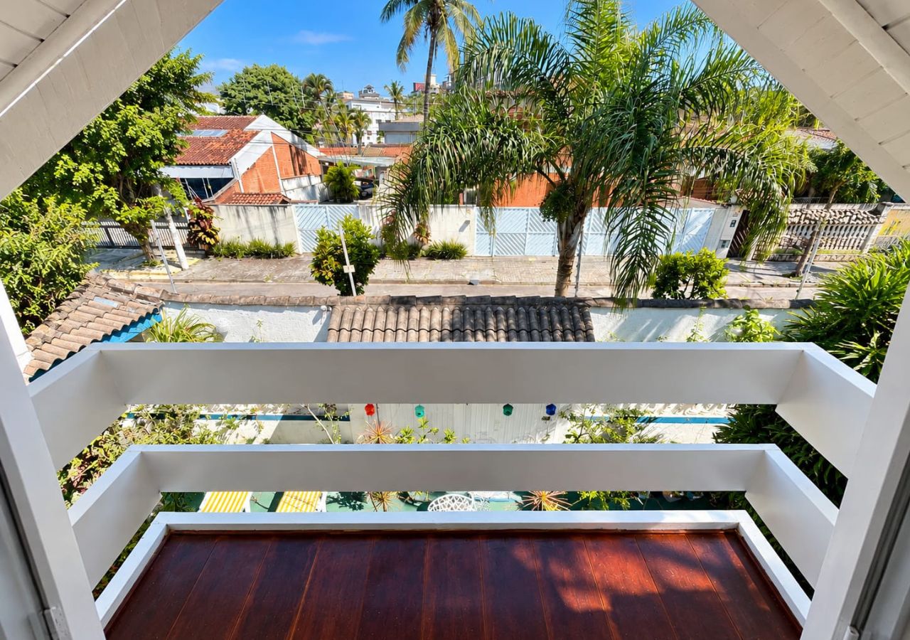 Un balcón con vista a una zona residencial, con casas y palmeras.