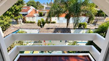 A balcony with a view of a residential area, including houses and palm trees.