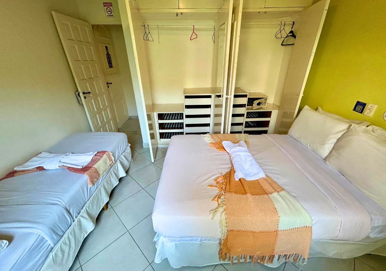 A room with two beds, a wardrobe, and a storage unit.