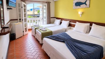 A hotel room with two beds, a television, a wall-mounted air conditioner, and a view through an open door.