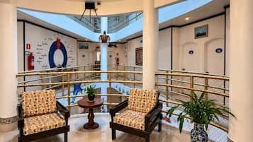 A lobby with two armchairs, a small table, and a potted plant.