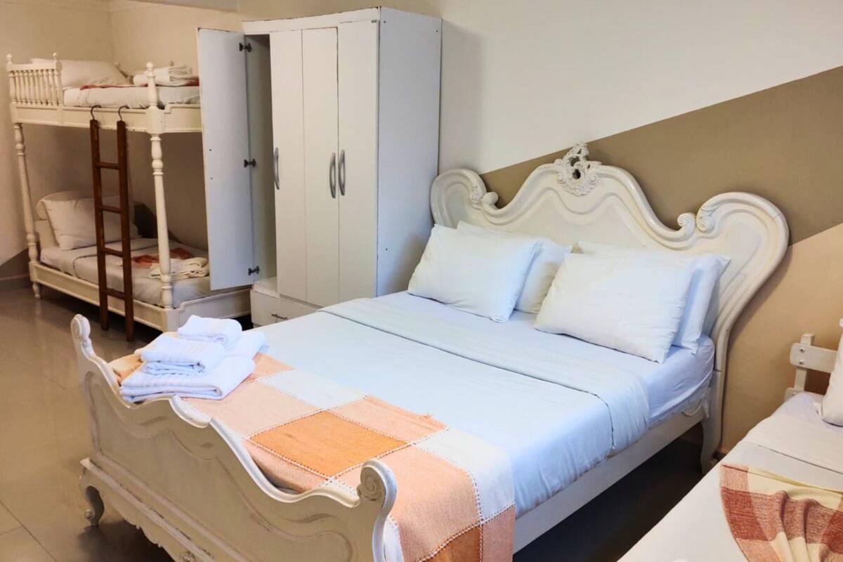 Une chambre bien rangée, avec un lit, une armoire et une petite table accompagnée d’une chaise.