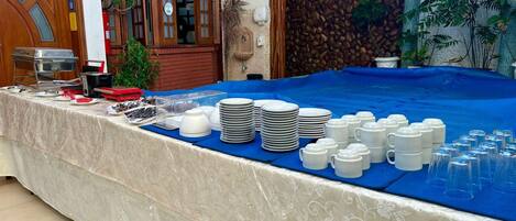 Una mesa de buffet con diversos platos y utensilios, un aparador de madera y un adorno en la pared.