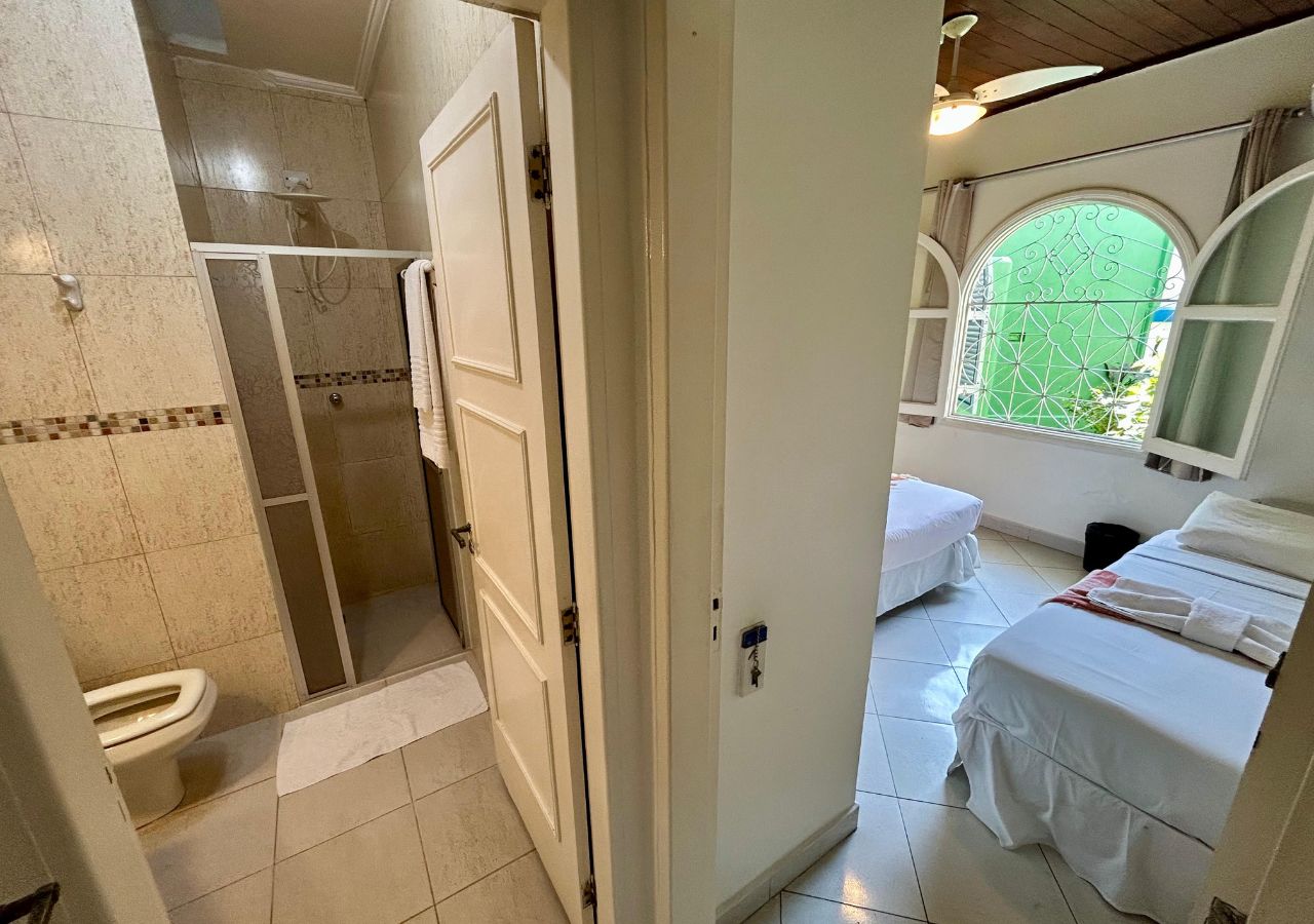 A bathroom with a shower, toilet, and a small window.