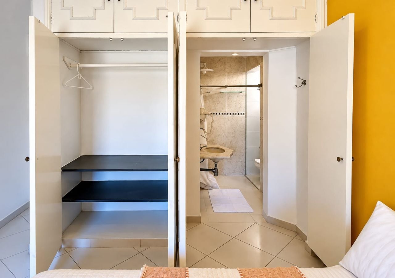 Una camera da letto con un letto, un armadio e un bagno con il water e un lavandino.
