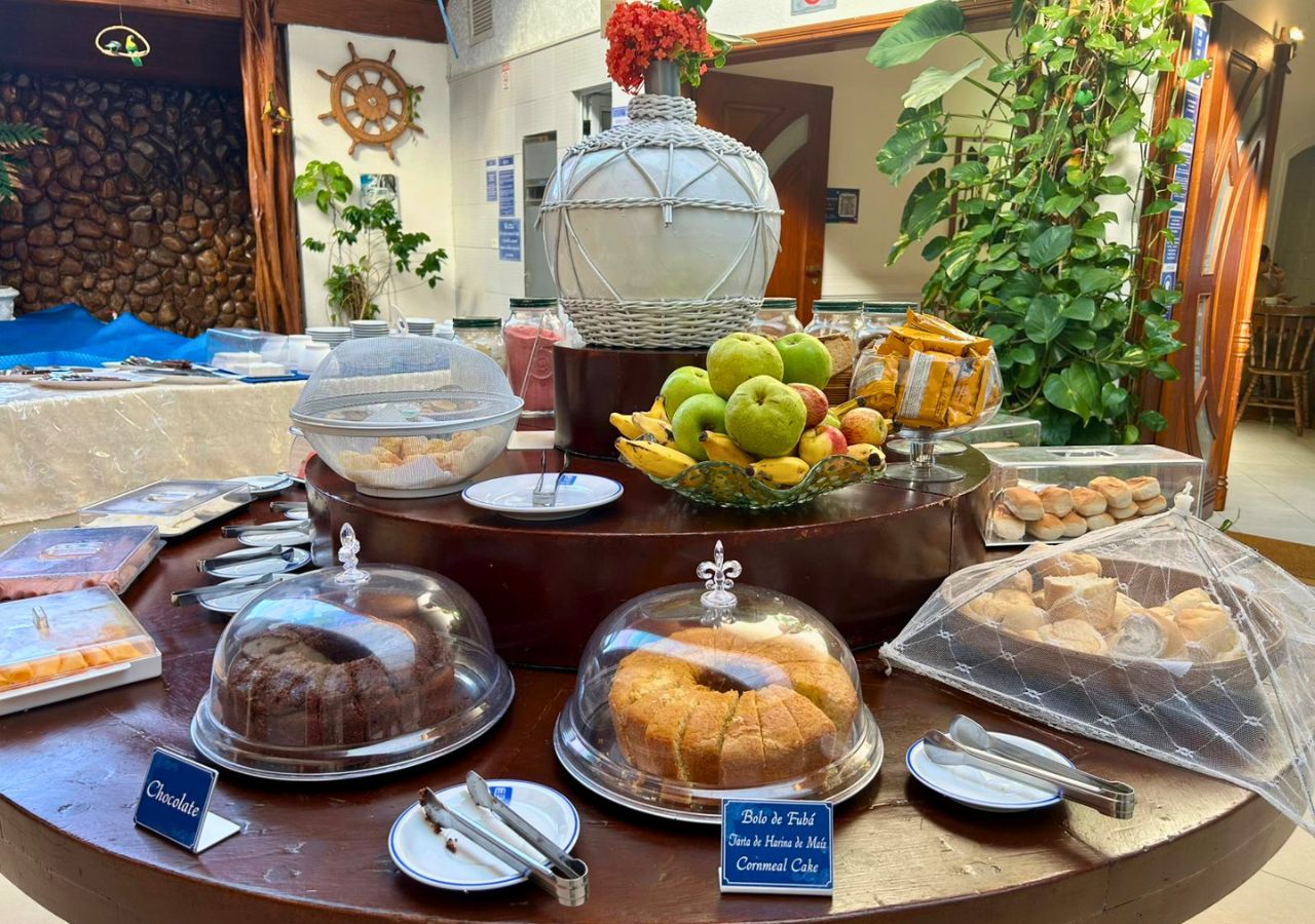 Een buffet met diverse gerechten, waaronder chocoladetaart, een fruitschaal en een afgedekte taartplateau.