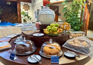 Un bufé con diversas opciones de comida, incluyendo un pastel de chocolate, un bol de fruta y un pastel cubierto.