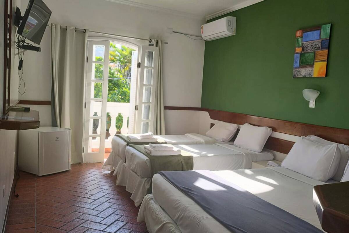 Une chambre d’hôtel avec deux lits, un petit bureau, un appareil de climatisation et une vue sur l’extérieur.