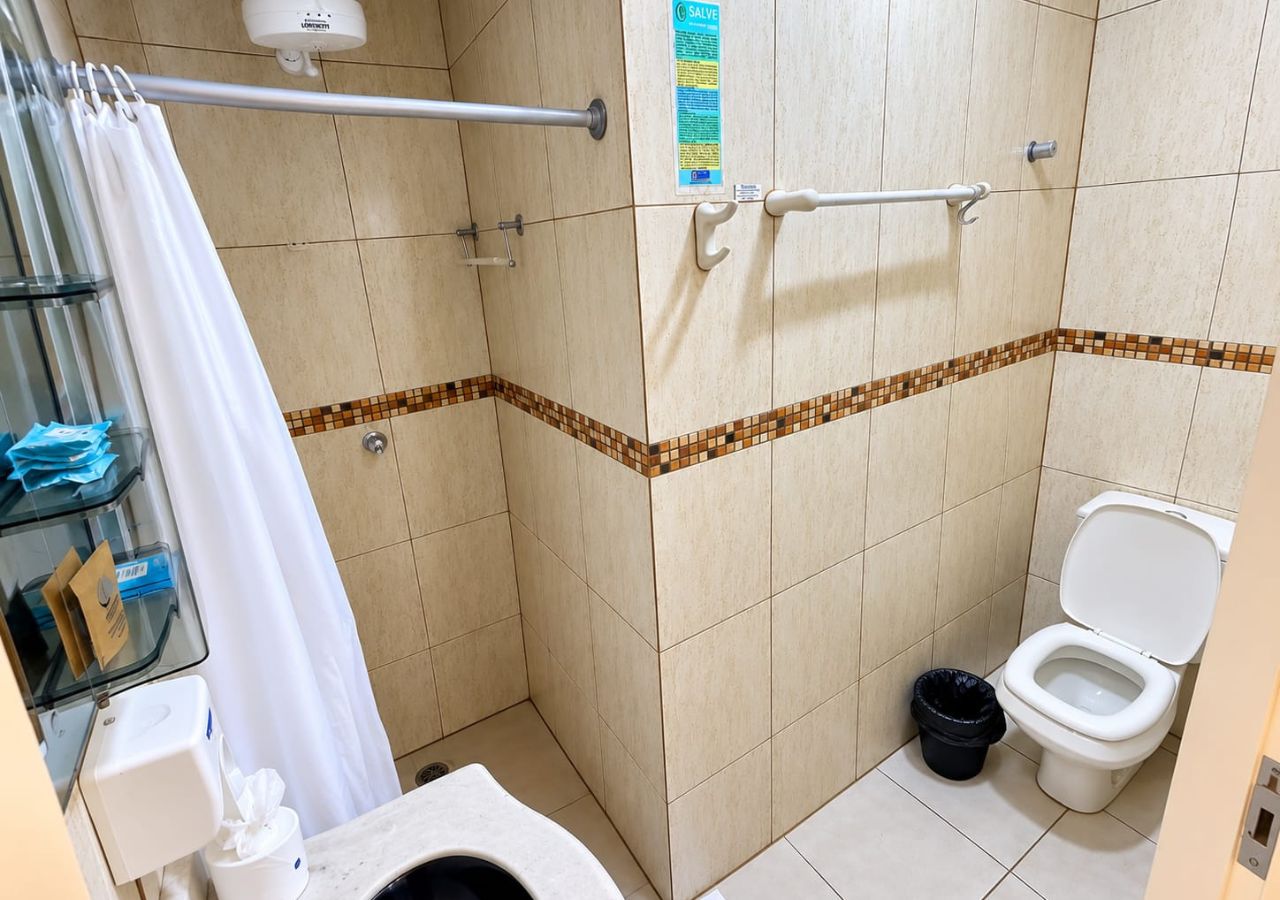 Une salle de bain équipée d’une douche, de toilettes et d’un distributeur de gel hydroalcoolique.