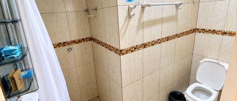 Un baño con ducha, inodoro y dispensador de gel antibacterial.