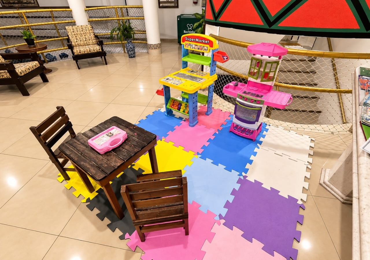 Un espace de jeux pour enfants avec une table, des chaises et des structures colorées.