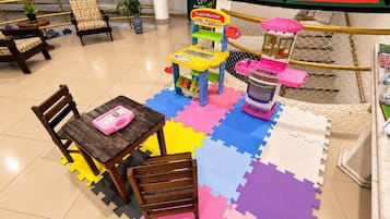 Un espace de jeux pour enfants avec une table, des chaises et des structures colorées.