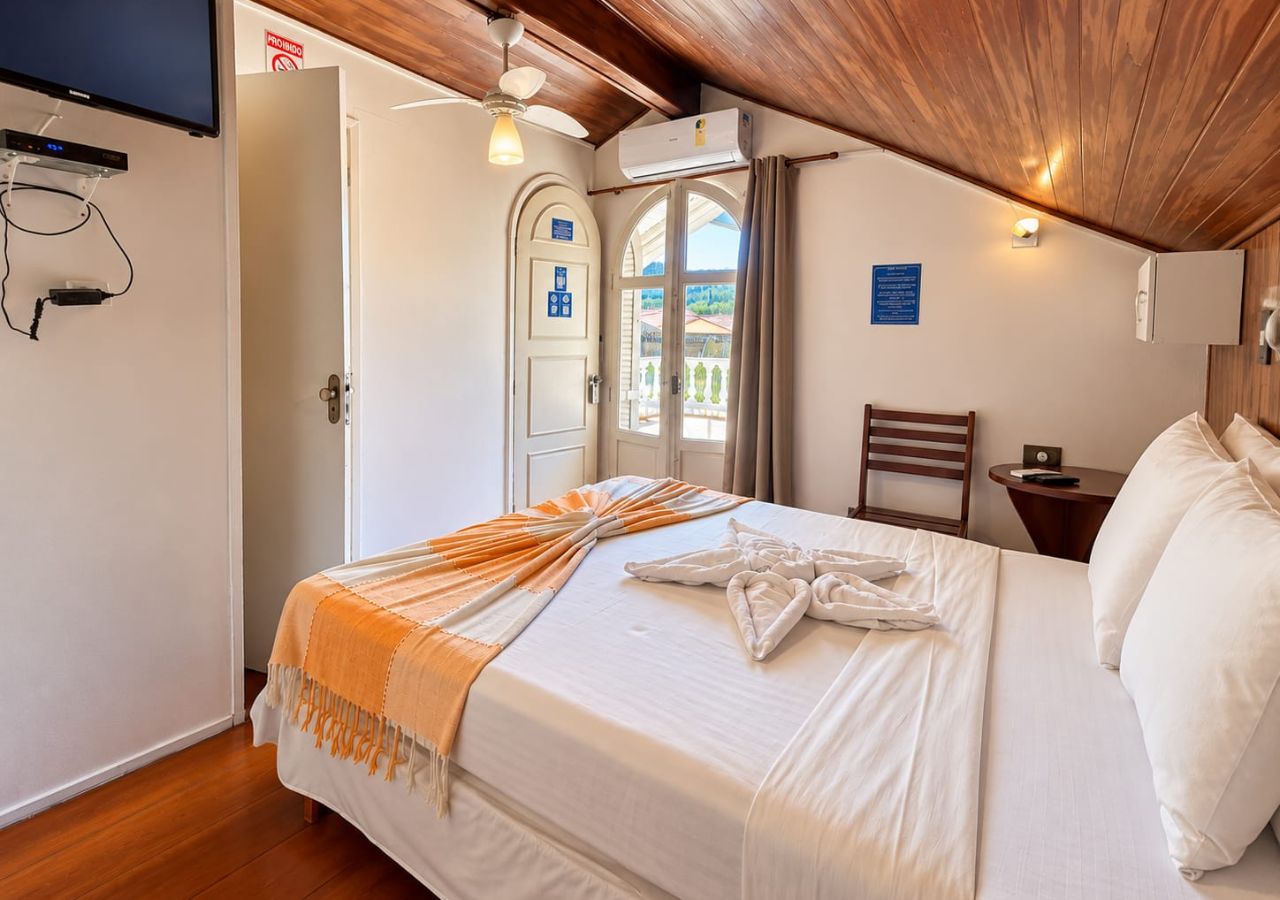Une chambre d’hôtel équipée d’un lit, d’une télévision, d’un système de climatisation et offrant une vue sur l’extérieur.