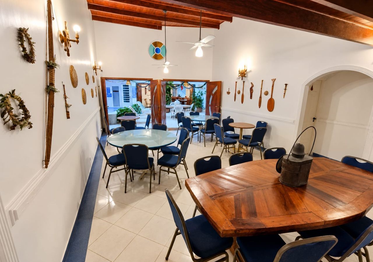 A dining area with round tables and blue chairs, a wooden accent table, and a ceiling fan.