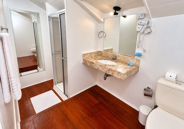 Un baño con ducha, inodoro y lavamanos con espejo.