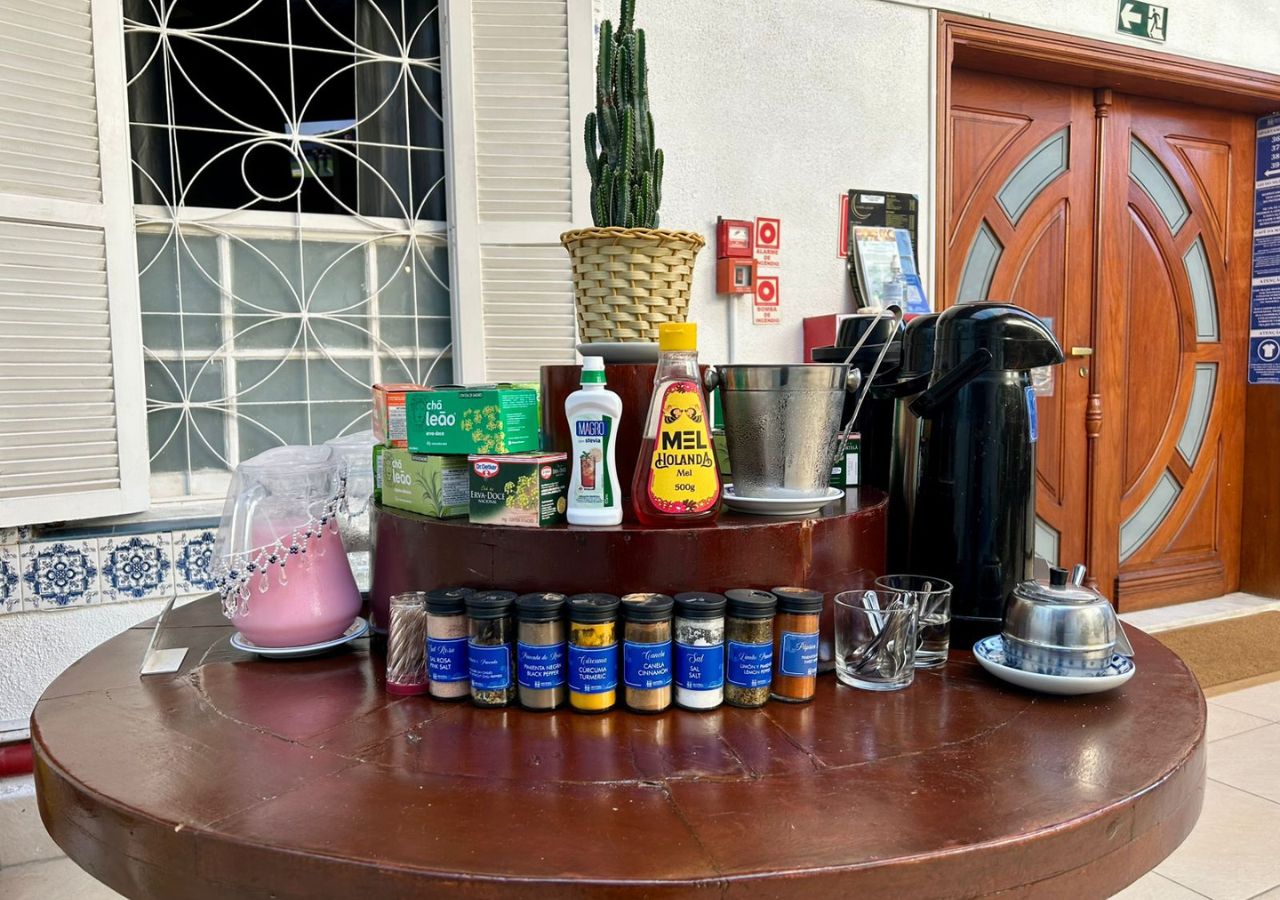 A table with various condiments, a coffee maker, and a cactus in a basket.