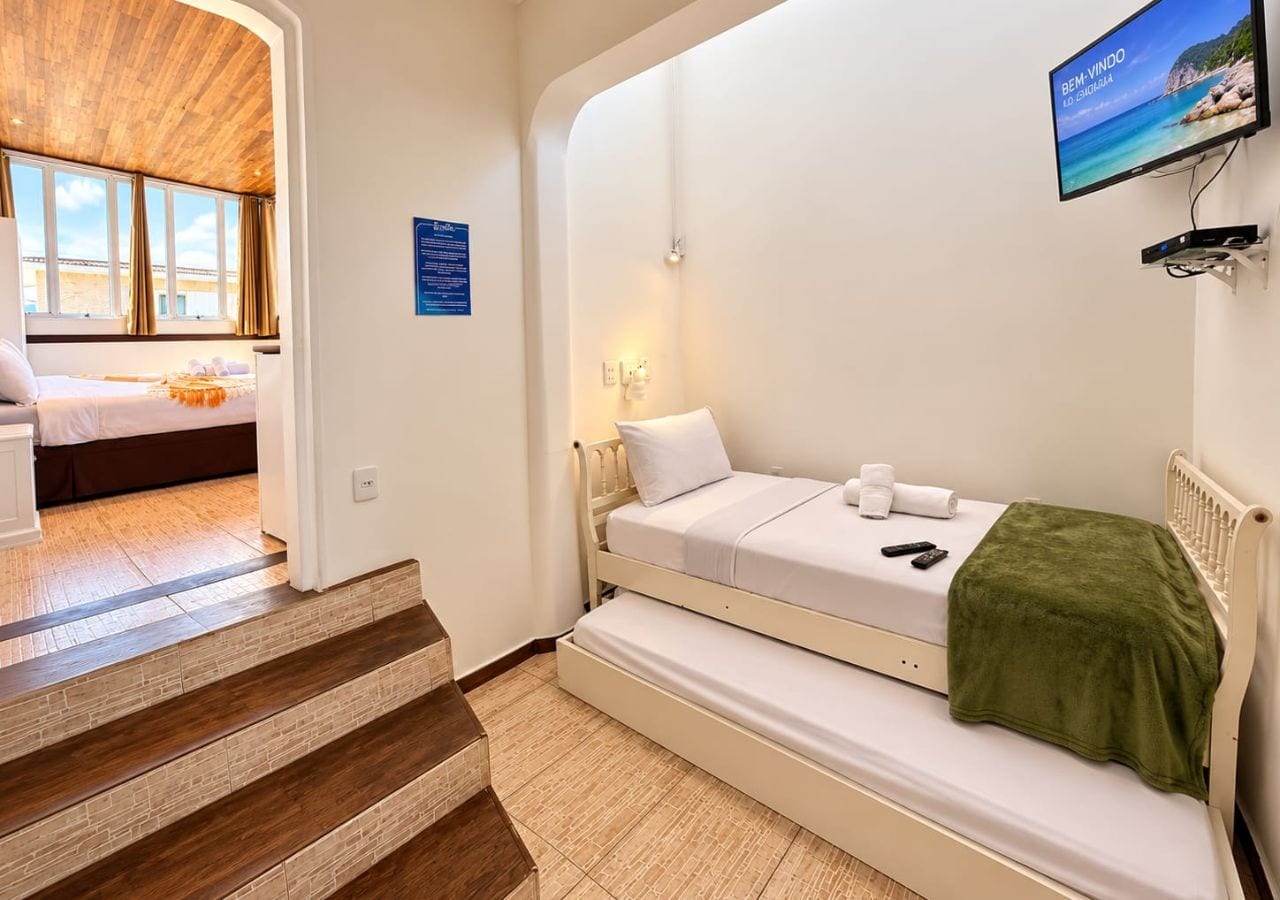A bedroom with a bed, a TV, and a staircase.