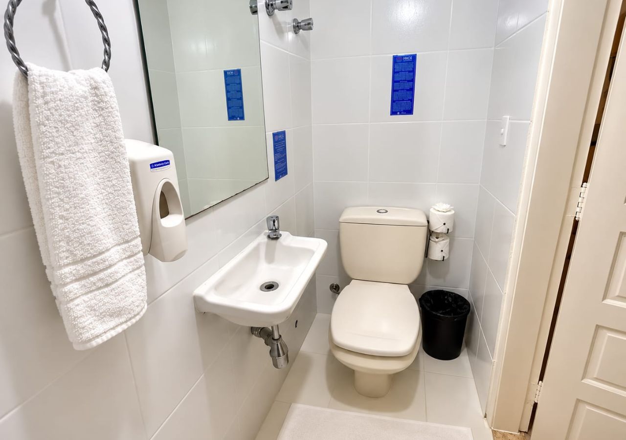 Casa de banho com lavatório branco, sanita e porta-toalhas.