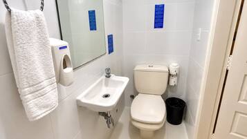 Casa de banho com lavatório branco, sanita e porta-toalhas.