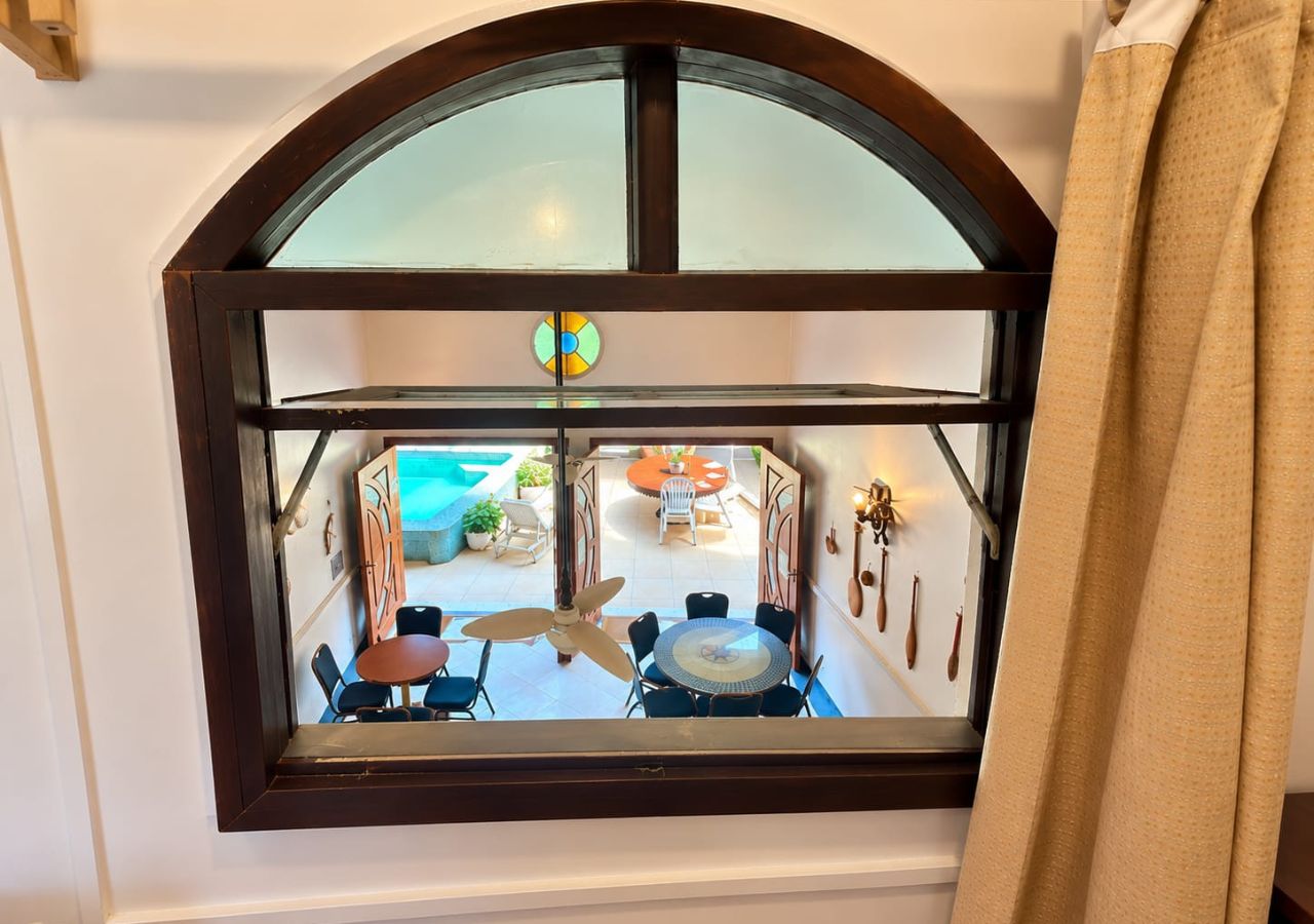 A room with a large arched window overlooking a pool area with outdoor furniture.