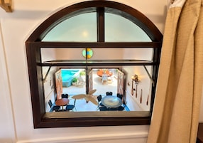 A room with a large arched window overlooking a pool area with outdoor furniture.