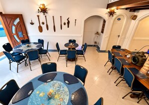 Ein Hotel-Speisesaal mit mehreren runden Tischen und blauen Stühlen, eine Holzwand mit Dekoration sowie die Zahl '37' an der Wand.
