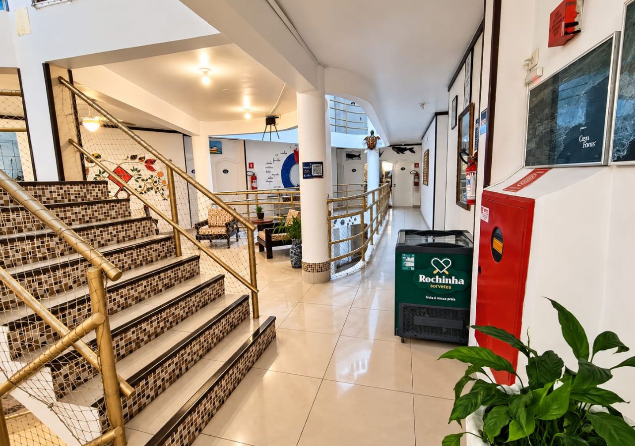 A hotel lobby with a staircase, seating area, and a green recycling bin.