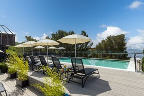A rooftop pool area with lounge chairs and umbrellas, surrounded by greenery and overlooking a body of water. - Hotel Ad Turres (Crikvenica)