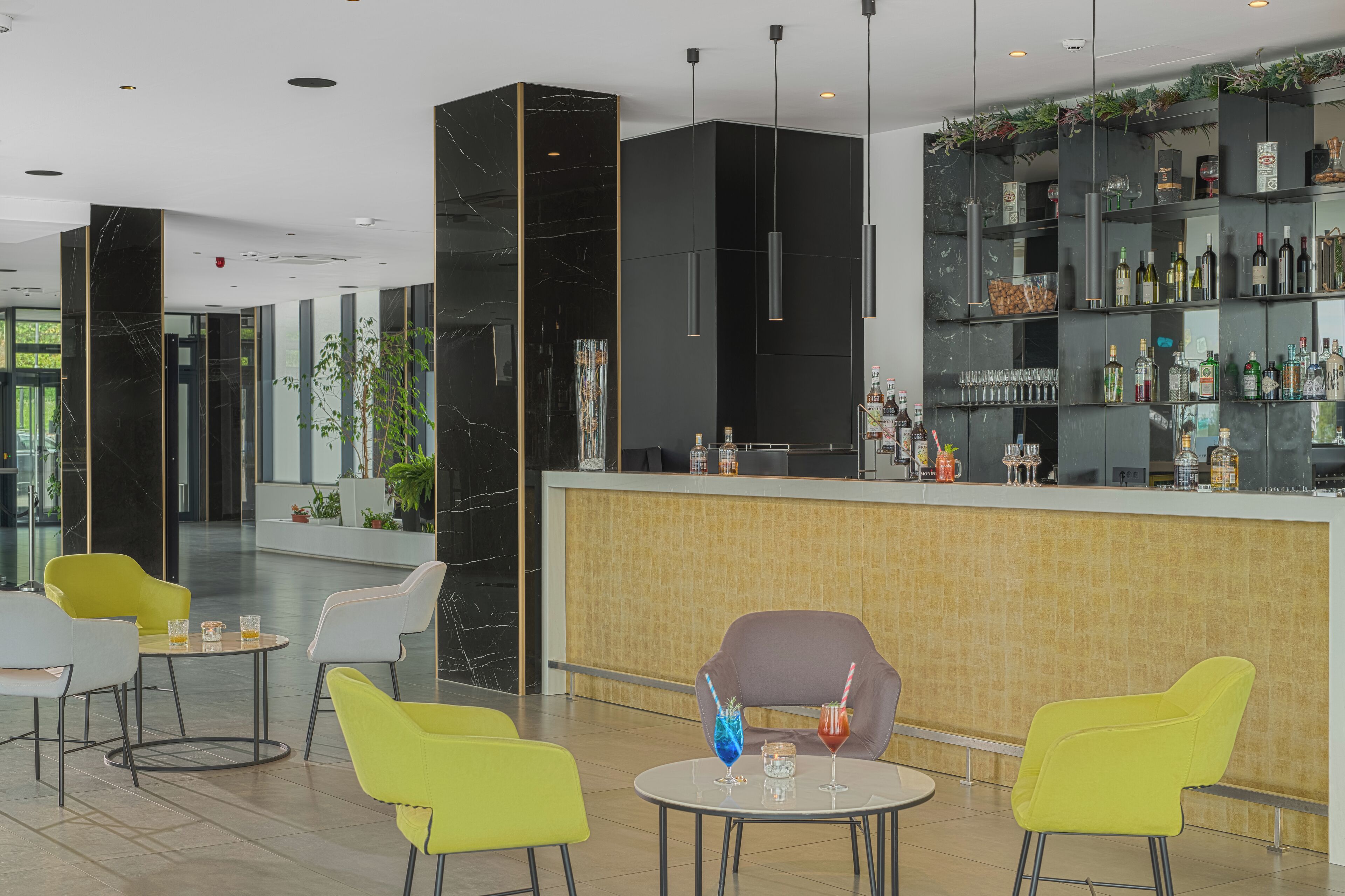 A modern bar area with a counter, seating, and a variety of bottles and glasses.