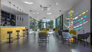 A modern bar area with a long counter, bar stools, and a seating area with chairs. - Hotel Ad Turres (Crikvenica)