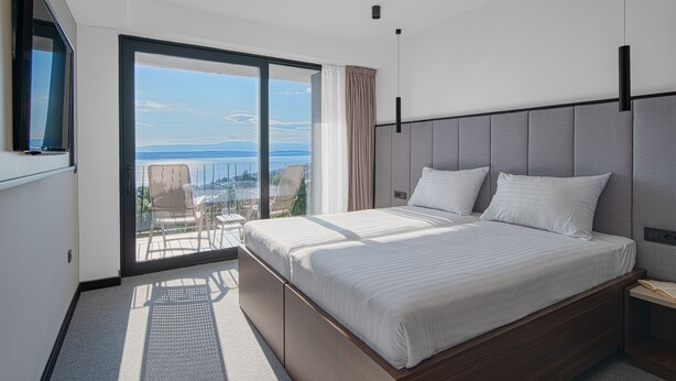 A modern bedroom with a large bed, a TV, and a balcony with a view. - Hotel Ad Turres (Crikvenica)