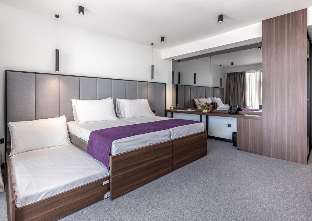 Una habitación de hotel moderna con una cama grande, un escritorio y un espejo.