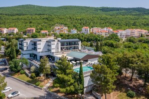 A modern hotel with a swimming pool, surrounded by lush greenery and hills. - Hotel Ad Turres (Crikvenica)
