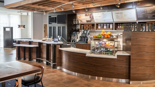 A modern coffee shop with a wooden counter, seating area, and menu boards.