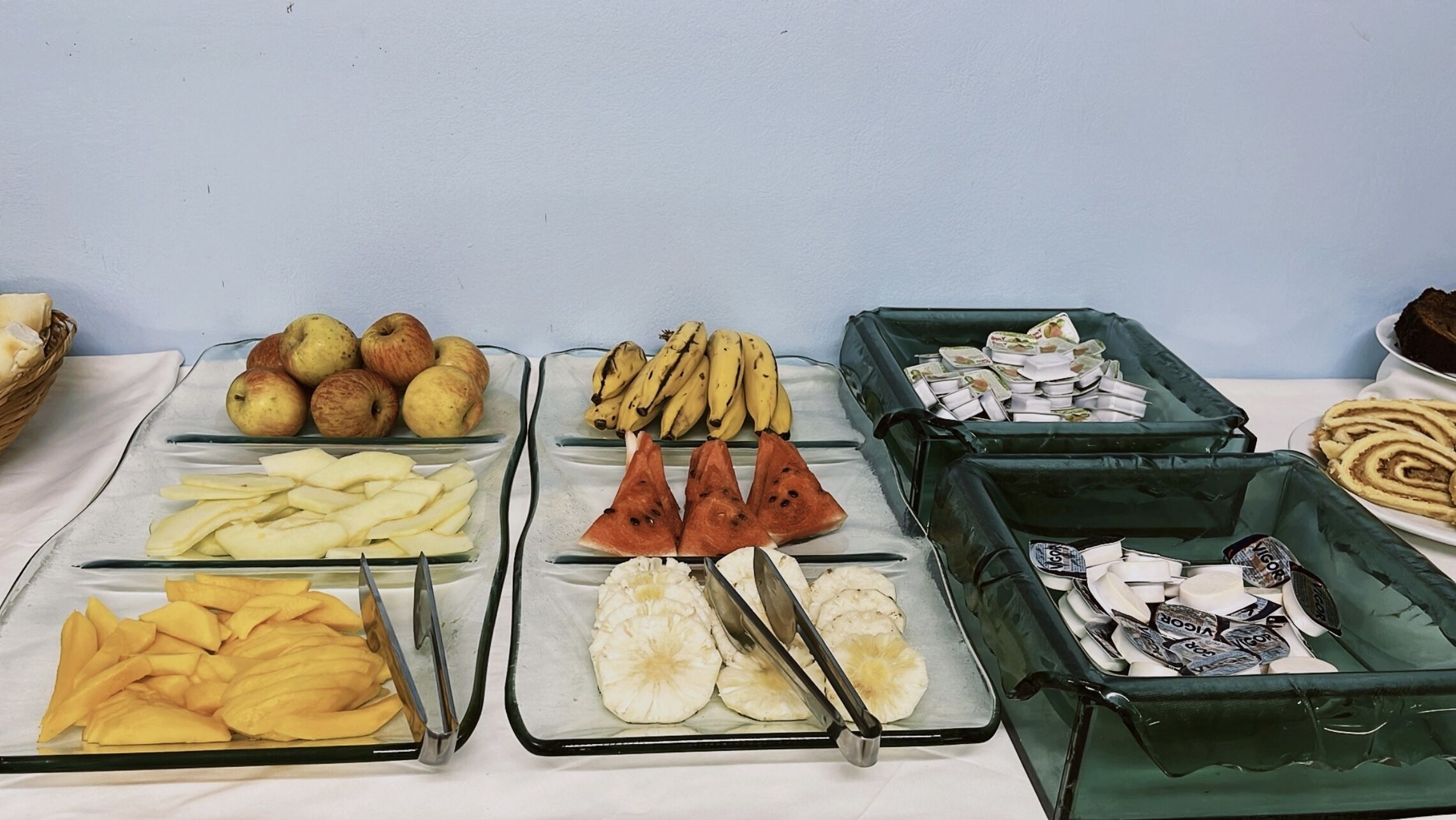 A buffet table with various fruits and vegetables, including apples, bananas, and watermelon slices.