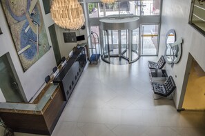 A lobby with a reception desk, a turnstile, and a seating area with a bench. - Mont Blanc Apart Hotel Duque de Caxias (Duque de Caxias)