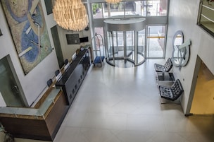 A lobby with a reception desk, a turnstile, and a seating area with a bench.