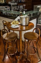 A bar area with a round table, two stools, a large metal pot, and a plate of food.