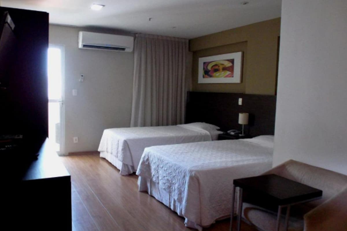 A hotel room with two beds, a TV, a desk, and a chair.