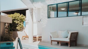 A pool area with a lounge chair, a small table, and a chair. - La Promenade Absolute Waterfront Apartments (Caloundra)